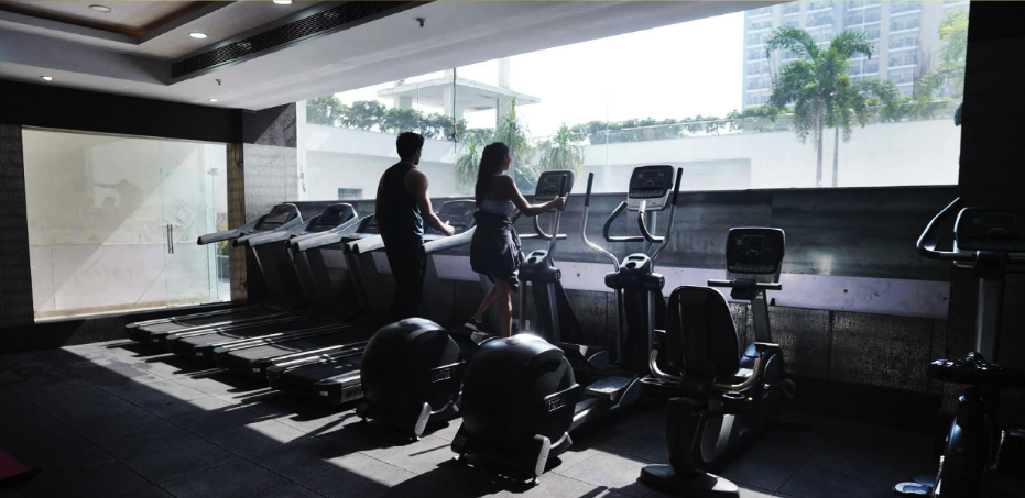 Panchsheel Greens II: fitness centre with cardio equipment and park view